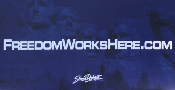 Image says FreedomWorksHere.com on blue background. Mount Rushmore in blue background. 